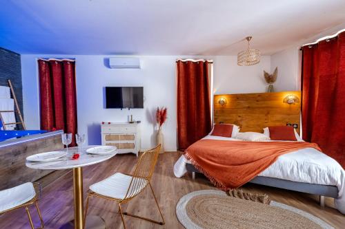 Schlafzimmer mit einem Bett mit roten Vorhängen und einem Tisch in der Unterkunft Loft Romantique - Spa Privatif - Spa Noctambulles in Hyères