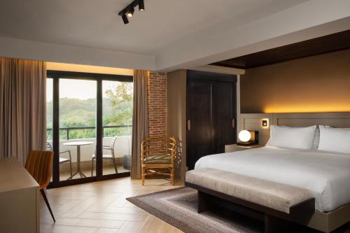 a bedroom with a bed and a balcony with a tub at Camp David Ranch in Santiago de los Caballeros
