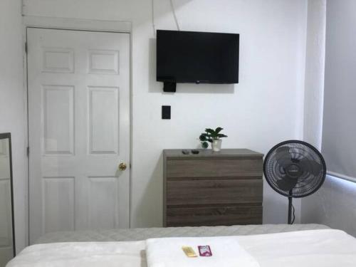 a bedroom with a bed and a fan and a television at Casa Colibrí Apartamento 7A in Guatemala