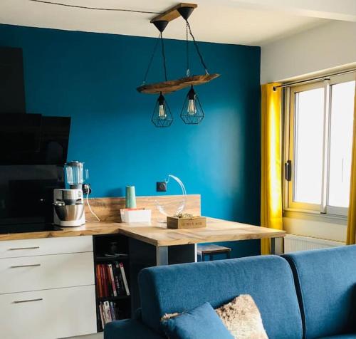 a kitchen with a blue wall with a table and a couch at Charmant T2 idéal CV parking privé à la résidence in Gap