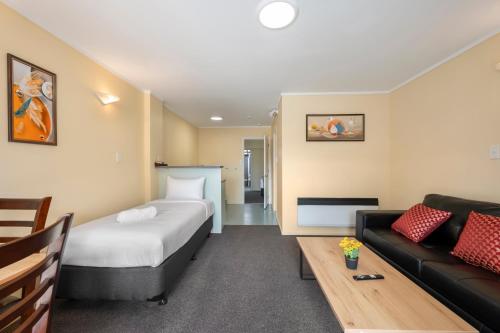 a hotel room with a bed and a couch at Fenton Court Motel in Rotorua