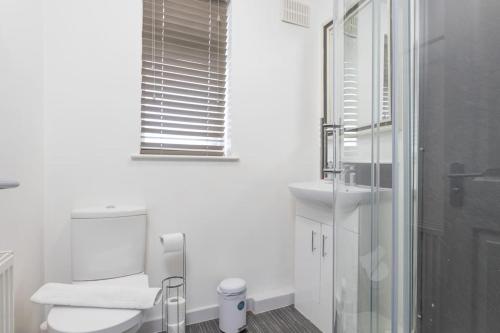 Baño blanco con aseo y lavamanos en Spacious 4 Bed house W/Free Parking Sleeps 7 Near Walsgrave Hospital en Wyken