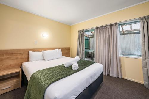 a hotel room with a bed and a window at Fenton Court Motel in Rotorua