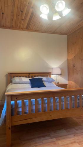 een groot houten bed in een slaapkamer met een plafond bij Eileen’s Cottage in Donegal
