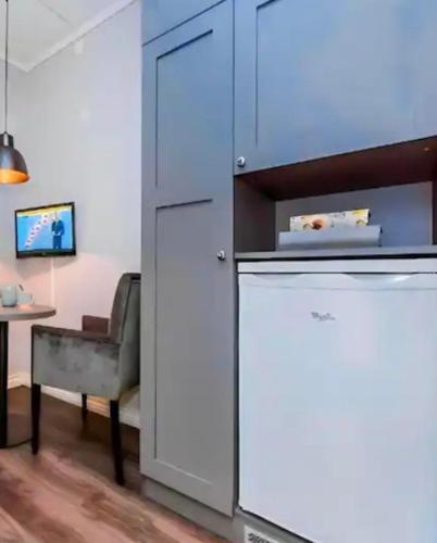cocina con armarios blancos, mesa y silla en Studio Apartments near Oslo Airport, en Garder