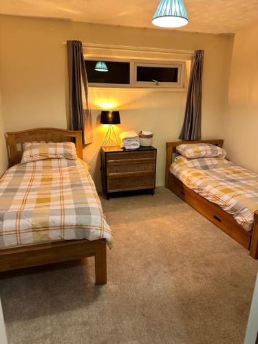 a bedroom with two beds and a table with a lamp at The Snug in Amlwch