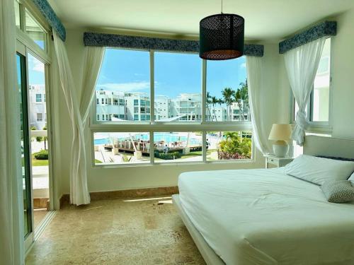 ein Schlafzimmer mit einem Bett und einem großen Fenster in der Unterkunft Gourgeous 2 bedroom Beach Apt Playa Nueva Romana in San Pedro de Macorís