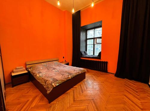 orangefarbenes Zimmer mit einem Bett und einem Fenster in der Unterkunft KyivHome Loft on Maidan Independence Square in Kiew