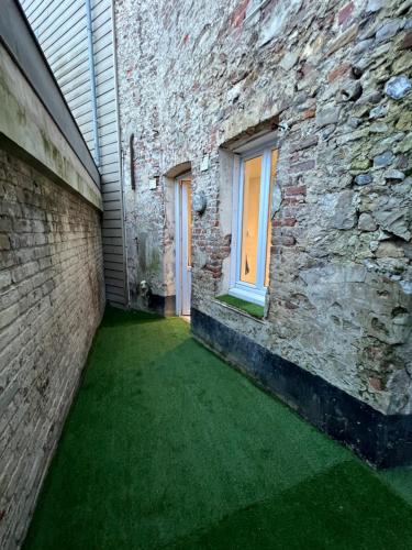 eine Gasse mit grünem Gras neben einem Backsteingebäude in der Unterkunft Au petit bonheur in Étaples