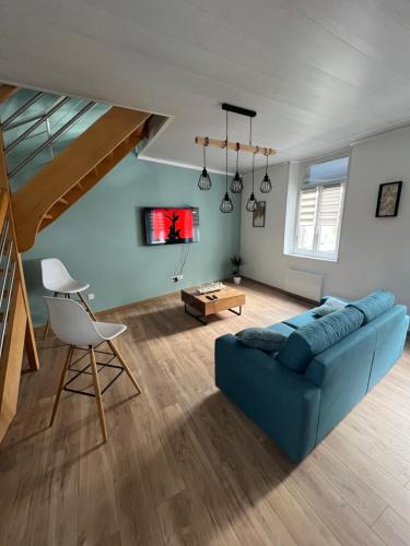 un salon avec un canapé bleu et une table dans l'établissement Au petit bonheur, à Étaples