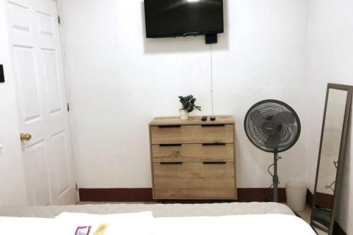 una camera da letto con ventilatore e comò con televisore di Casa Colibrí Apartamento 7C a Guatemala