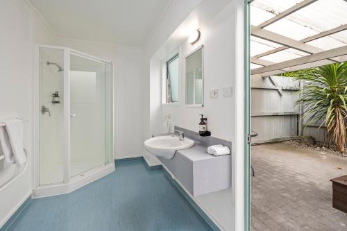 a white bathroom with a sink and a shower at Fenton Court Motel in Rotorua