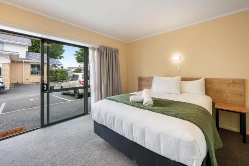 a bedroom with a bed and a large window at Fenton Court Motel in Rotorua