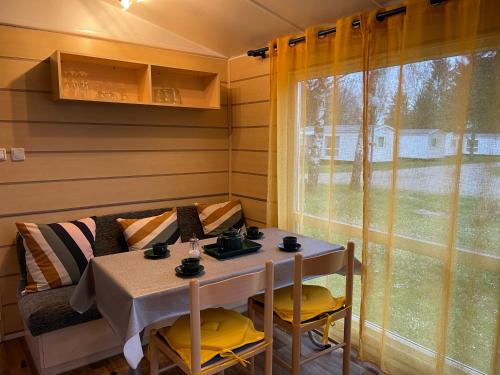 ein Esszimmer mit einem Tisch und einem Fenster in der Unterkunft *Air-conditioned* Mobilhome near Europapark in Boofzheim