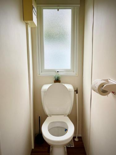 a bathroom with a toilet with a window at *Air-conditioned* Mobilhome near Europapark in Boofzheim