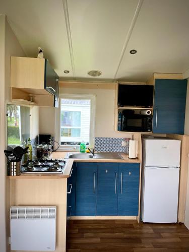 a kitchen with blue cabinets and a white refrigerator at *Air-conditioned* Mobilhome near Europapark in Boofzheim