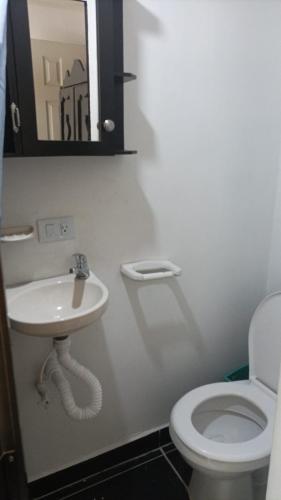 ein Badezimmer mit einem WC, einem Waschbecken und einem Spiegel in der Unterkunft Casa Estudiantil Sevillana in Medellín