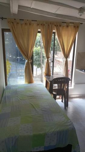 Schlafzimmer mit einem Bett, einem Tisch und Fenstern in der Unterkunft Casa Estudiantil Sevillana in Medellín