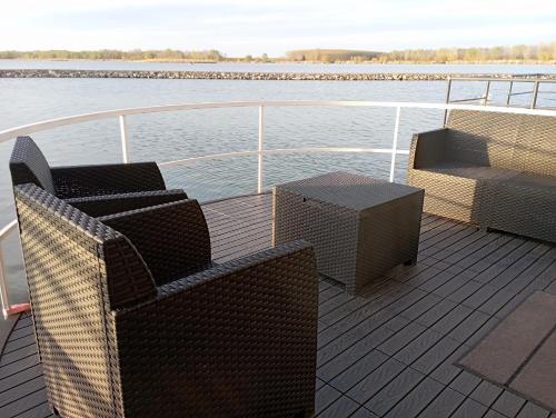 a deck with two chairs and a table on a boat at Koncér úszóház in Abádszalók
