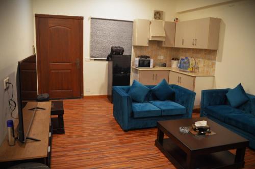 een woonkamer met twee blauwe banken en een keuken bij LandmarkIII Apartment in Islamabad