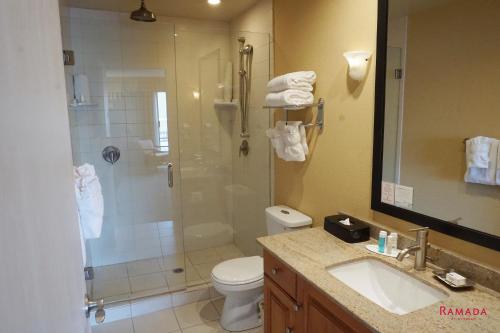 a bathroom with a shower and a toilet and a sink at Ramada by Wyndham Kelowna Hotel & Conference Center in Kelowna