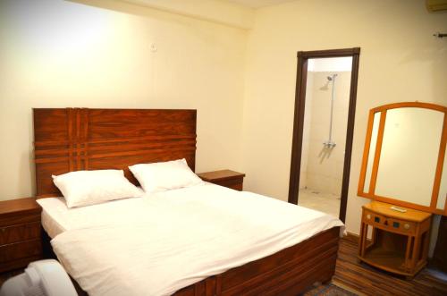 een slaapkamer met een bed met een houten hoofdeinde en een spiegel bij LandmarkIII Apartment in Islamabad