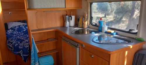 eine Küche mit einem Waschbecken und einem Fenster in einem Wohnwagen in der Unterkunft Caravan Finca La Vida Rustica in Maella