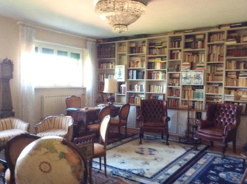 a library with chairs and a table and books at Villa Nanda a 15 minuti da Roma piscina esclusiva , villa nella natura in Formello