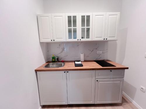 eine Küche mit weißen Schränken und einem Waschbecken in der Unterkunft Apartman No. 2 in Zagreb
