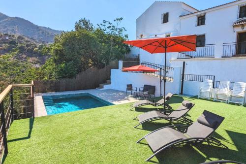 a yard with chairs and an umbrella and a swimming pool at Casa Rural Pagalván in Málaga