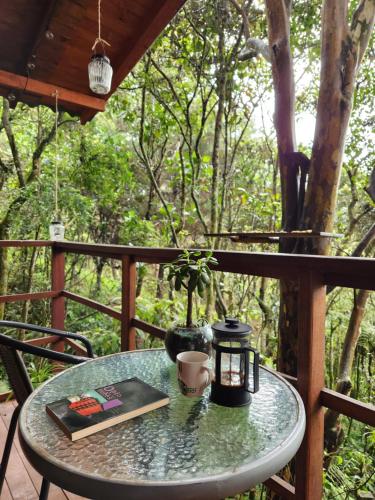 a table with a book and a coffee cup on a porch at Cabaña en Medio del Bosque con Jacuzzi - Santa Elena in Santa Elena
