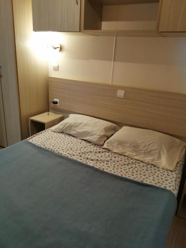 un lit dans une petite pièce avec une tête de lit dans l'établissement Mobil home 6 personnes climatisé ., à Port-la-Nouvelle