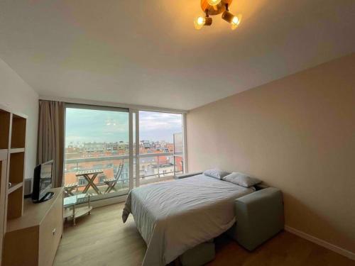 a bedroom with a bed and a large window at Fully renovated studio with nice view! in Nieuwpoort