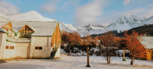 a house with snow covered mountains in the background at Wyndham Garden Ushuaia Hotel del Glaciar in Ushuaia