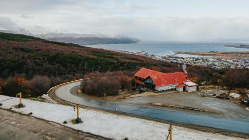 a house with a red roof next to a road at Wyndham Garden Ushuaia Hotel del Glaciar in Ushuaia