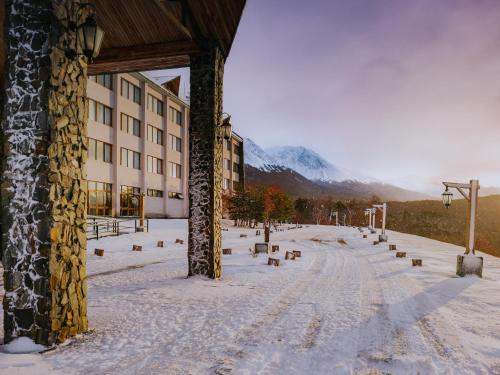 a snow covered street with a building and a mountain at Wyndham Garden Ushuaia Hotel del Glaciar in Ushuaia