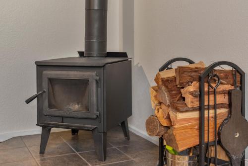 a black stove sitting next to a pile of logs at Faeya Grove in Forestville