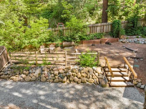 a garden with a wooden fence and a rock wall at Faeya Grove in Forestville