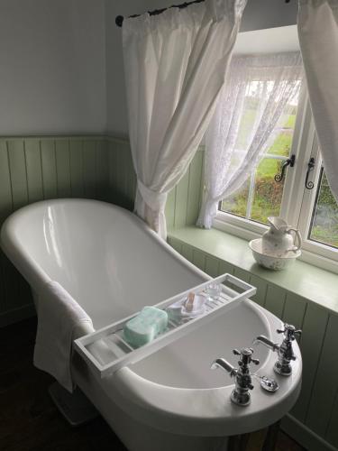 baño con bañera blanca y ventana en Christie's Cottage, en Dungiven