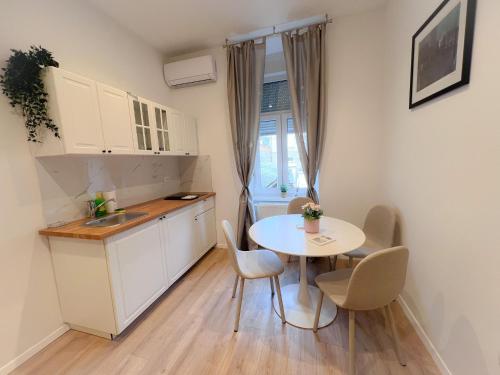 Apartman No. 3 في زغرب: مطبخ صغير مع طاولة بيضاء وكراسي