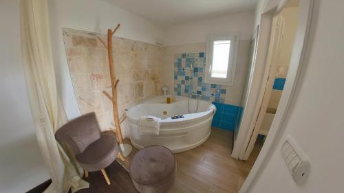 uma casa de banho com uma banheira e uma cadeira. em Le Casette em Martina Franca