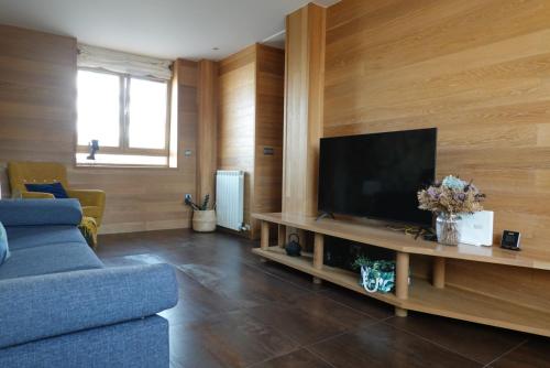 Vitoria-Gasteiz magnífica casa في فيتوريا جاستيز: غرفة معيشة مع أريكة زرقاء وتلفزيون بشاشة مسطحة
