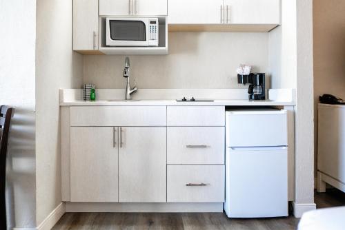 a kitchen with white cabinets and a microwave at Perry's Ocean-Edge Resort in Daytona Beach