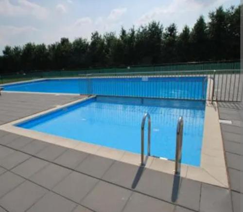a large swimming pool with blue water at Newly renovated luxurious Villa / hottub / sauna / 7 bedrooms in Zeewolde