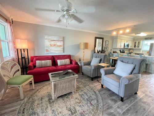a living room with a red couch and chairs at Jubilee Landing 107 in Orange Beach