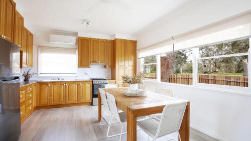 a kitchen with wooden cabinets and a table with white chairs at Bungalow 21 in Callala Beach