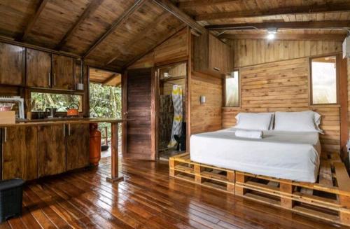 a bedroom with a bed in a wooden cabin at Cabaña en Medio del Bosque con Jacuzzi - Santa Elena in Santa Elena