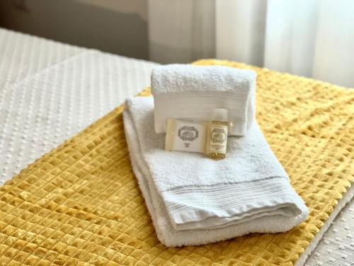 een stapel handdoeken en een fles zeep op een bed bij Casa Sebastião in Faro
