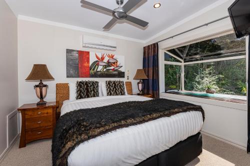 1 dormitorio con 1 cama, ventilador de techo y ventana en Sanctuary Palms, en Paihia