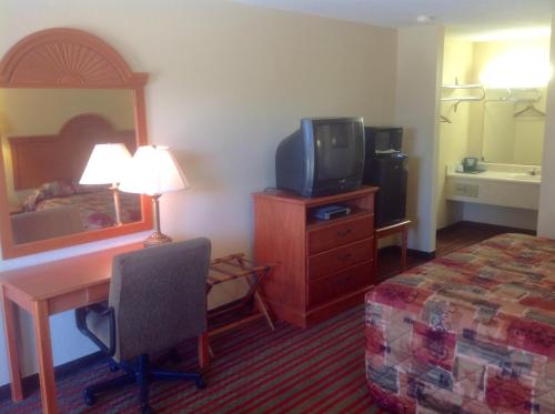 a hotel room with a bed and a desk and a tv at Western Motel - Jesup in Jesup